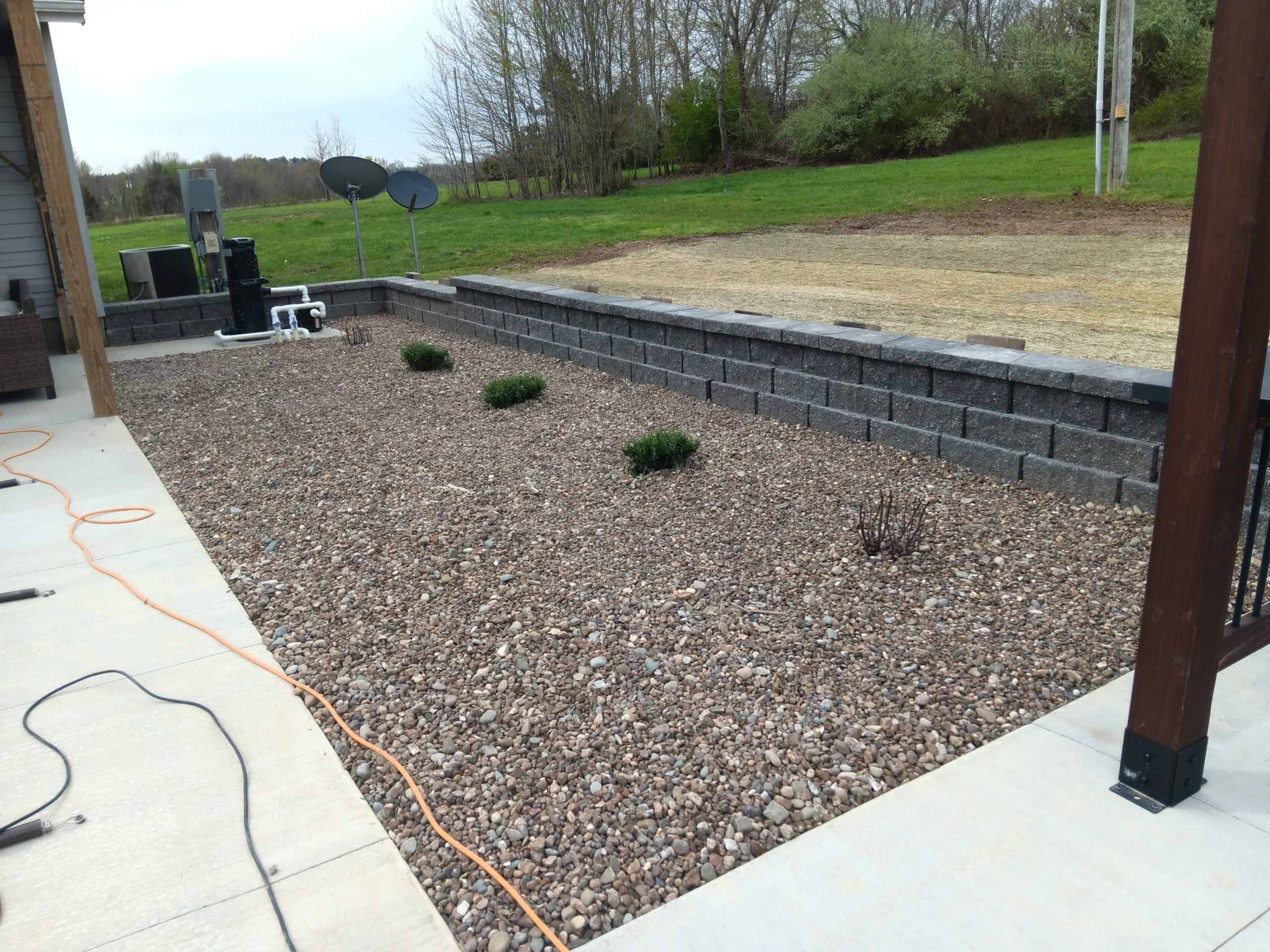 a safe outdoor living area with pavement, gravel, and a stone retaining wall