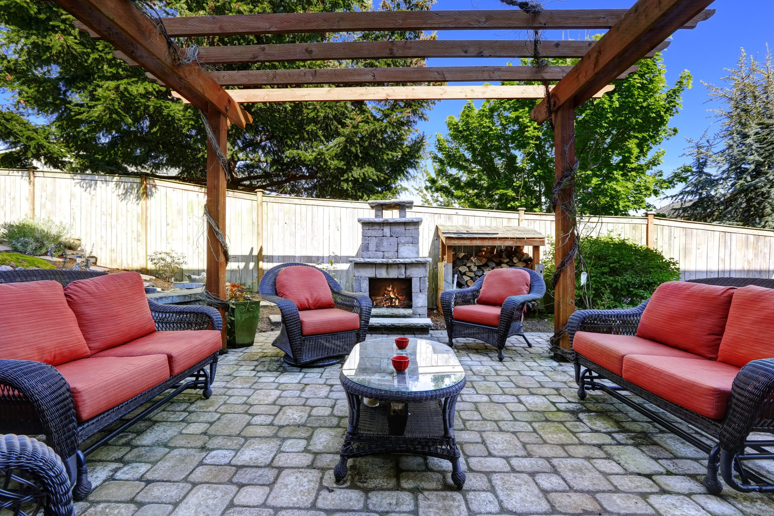 go perfection mulching austin tx decorative and functional mulch scaled - Perfection Lawn & Landscape LLC A paver patio with red, cushioned wicker seating, a pergola, and an outdoor fireplace creates a cozy backyard entertainment space.